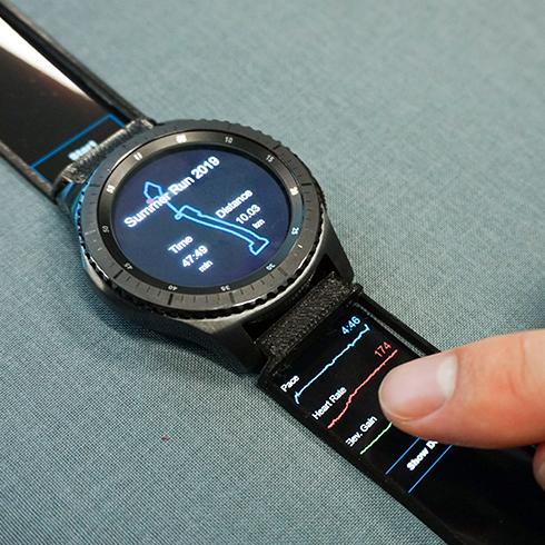 The image shows how interactive StrapDisplays can be utilzed to extend an acitvity tracker application on a smart watch. Therefore, additional information such as pace or heart rate are shown as dynamic graphs on the strap.